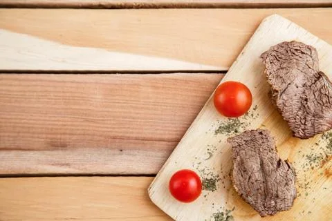 Chunks of deep-fried meat, steak on a wooden tray with spices and cherry toma Stock Photos