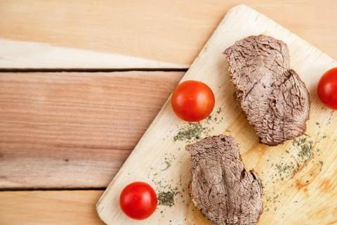 Chunks of deep-fried meat, steak on a wooden tray with spices and cherry toma Stock Photos