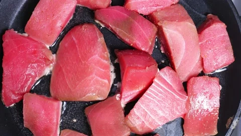 Chunks of fresh tuna are cooked in a hot skillet Stock Footage 147452960