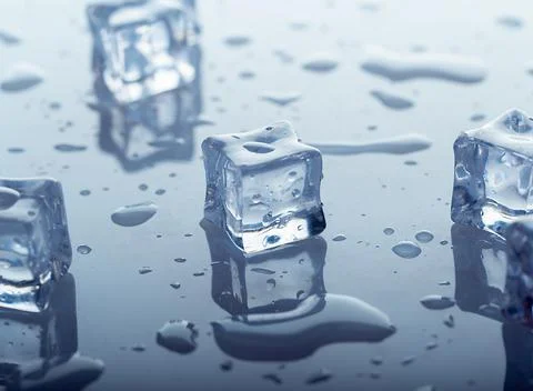 Chunks of frozen ice on a glossy surface with drops of clear water Stock Photos