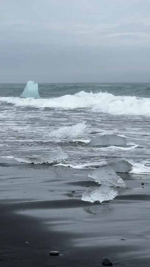 Chunks of glacial ice scattered on the black volcanic sands of Diamond Beach Stock Footage 312232857