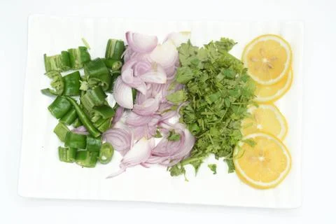 Chunks of green chilli, onion, celery leaves, and lemon on the rectangle plate Stock Photos