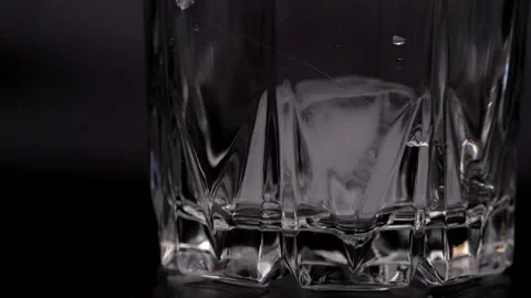 Chunks of ice fall into the glass. Ice cubes in a glass on a black background. Stock Footage 156869332