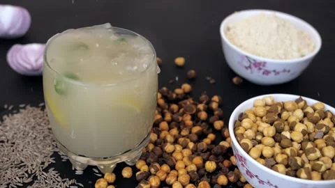 Chunks of ice falling in a glass of Sattu drink decorated with chilies and lemon Video stock 155824848