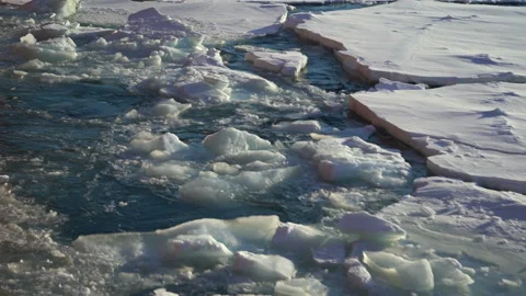 Chunks of ice in the water float by. Thick chunks of blue ice float in the water Stock Footage 143674063