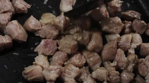 Chunks of meat cooking in a frying pan, with visible sizzling and browning Stock Footage 334320900
