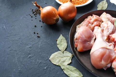 Chunks of raw chicken, tightly stacked in a frying pan, surrounded by seasoni Stock Photos