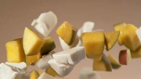 Chunks of white chocolate and mango flying in slow motion.  Shot with Phantom Stock Footage 130355985