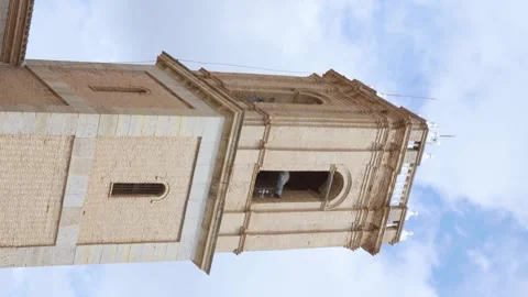 Church bell tower with bells ringing against a blue sky. Vertical video Stock Footage 255116396