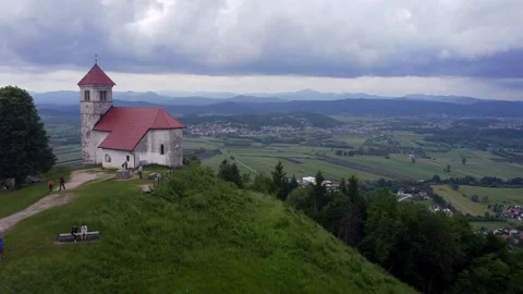 Church on a hill with trail and people - aerial forward opening a view Stock Footage
