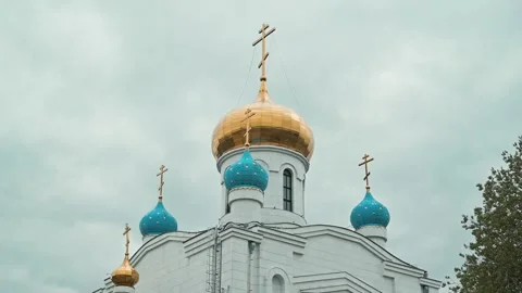 A church stands tall with golden domes and blue accents. The sky is filled with Stock-Footage 339094341