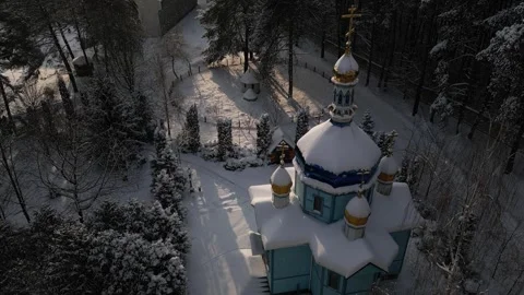 Church with thick layer of snow resting on roof stands in middle of dense park Stock Footage 326967102