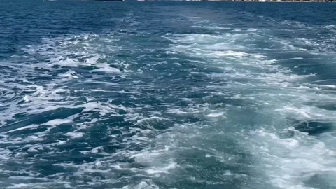 Churning ocean waves behind a moving boat on a sunny day Stock Footage 345259399