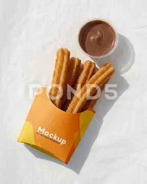 Churros inside packaging with separate chocolate filling cup on top of white pap PSD Template