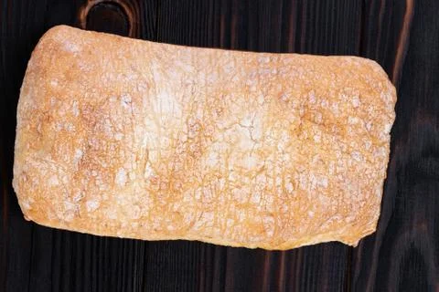 Ciabatta bread on a cutting board on the dark wooden table, top view with spa Stock Photos