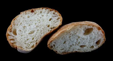 Ciabatta, a loaf of bread cut in half isolated on a black background. Stock Photos