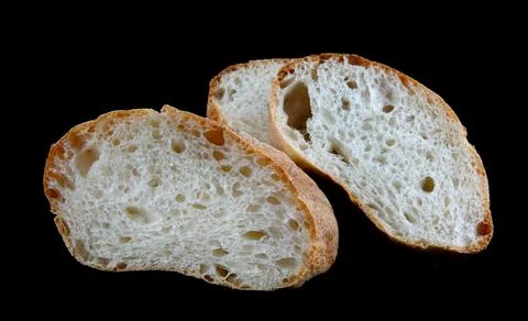 Ciabatta, a loaf of bread cut in half isolated on a black background. Stock Photos