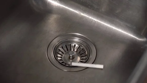 Ciagarettes are dropping into a sink and the tap is turned on. Stock Footage 69944992