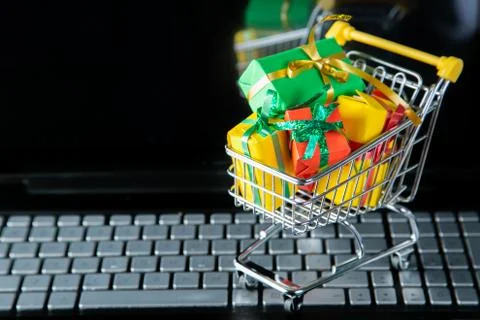 Ciber monday concept - trolley cart with christmas presents on notebook Stock Photos