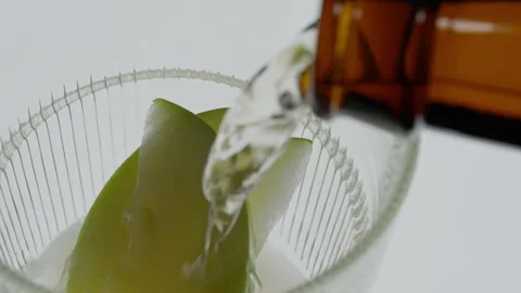 Cider Pour Into Glass With Apple Slice on White Studio Backdrop, Golden Liquid Video stock 305461762