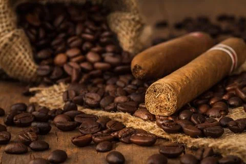 Cigar and coffee bean in small sack on the wooden table Stock Photos