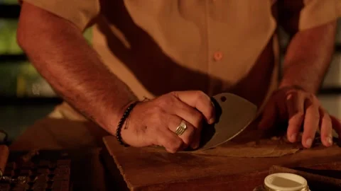Cigar Maker Crafts a Hand Rolled Cuban Cigar in a Lounge Cutting Tobacco Leaves Stock Footage 288038860