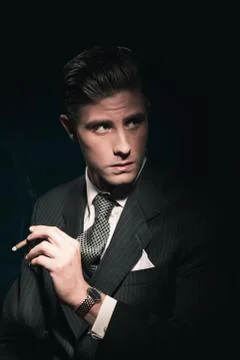 Cigar smoking retro 40s businessman in suit and tie. Hair combed back. Agains Stock Photos