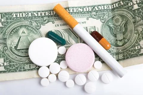 Cigarette and few pills on dollar banknote. Stock Photos
