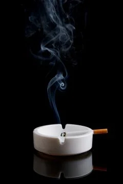 Cigarette in an ashtray on black Stock Photos