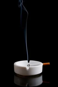 Cigarette in an ashtray on black Stock Photos