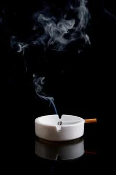 Cigarette in an ashtray on black Stock Photos