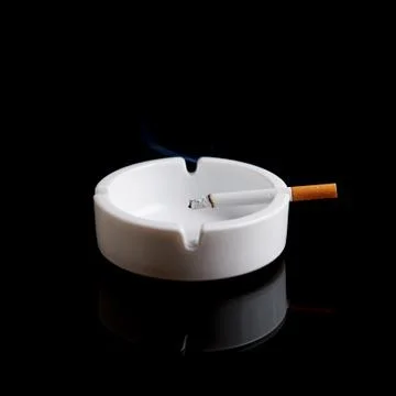 Cigarette in an ashtray on black Stock Photos