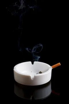 Cigarette in an ashtray on black Stock Photos