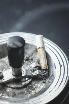 Cigarette on an ashtray on a dark background Stock Photos