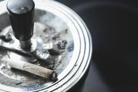 Cigarette on an ashtray on a dark background Stock Photos