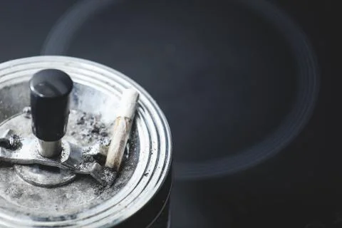Cigarette on an ashtray on a dark background Stock Photos