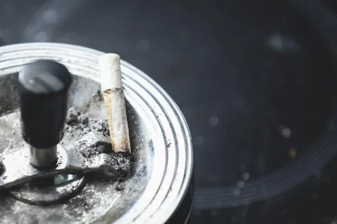 Cigarette on an ashtray on a dark background Stock Photos