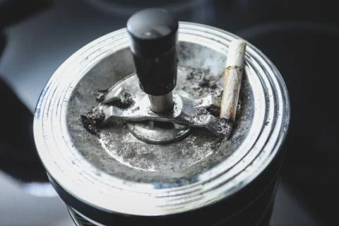Cigarette on an ashtray on a dark background Stock Photos