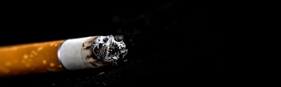 Cigarette butt on a black background. Panoramic image Stock Photos