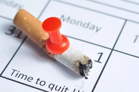 Cigarette butt impaled on calendar 库存照片