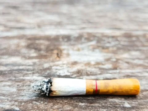 Cigarette Butt on Wooden Surface Representing Pollution Stock Photos