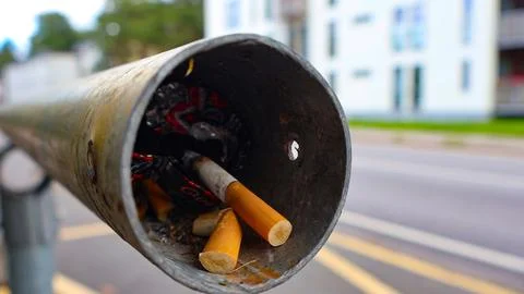 Cigarette butts and garbage creating street pollution in urban area Stock Photos