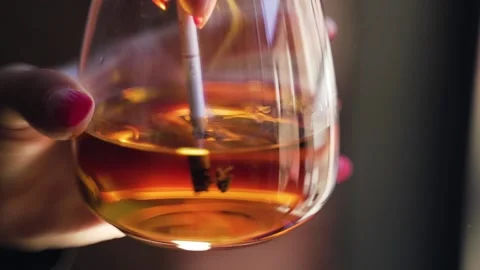 Cigarette is extinguished in a glass of whiskey Stock Footage 140286767