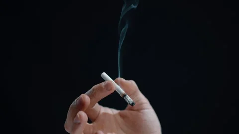 Cigarette in Hand Against a Black Background Stock Footage 295219749