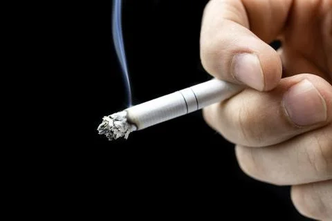 Cigarette hand black background Stock Photos