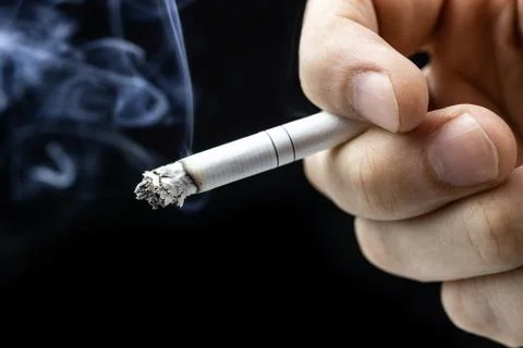 Cigarette hand black background Stock Photos