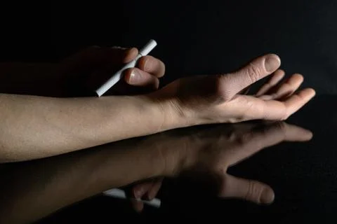 Cigarette in hand on black background with reflection. Foto stock