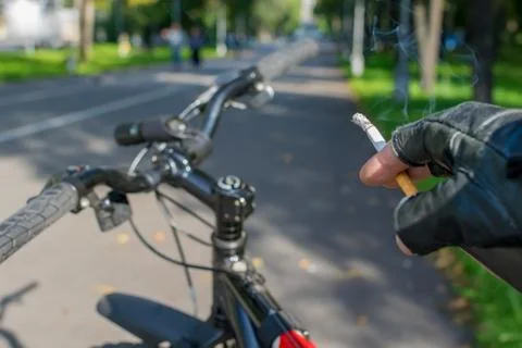 Cigarette in the hand of a smoking cyclist Stock Photos