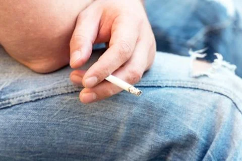 Cigarette in the hands of a seated man Foto stock