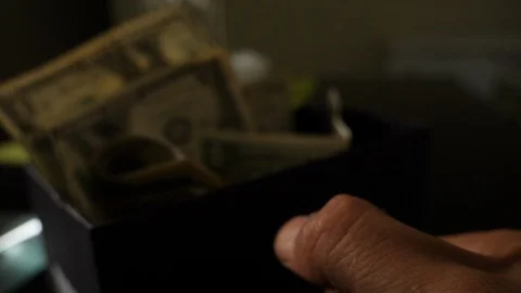 A cigarette lighter emits a flame with dollar bills in a box Stock Footage 109330988